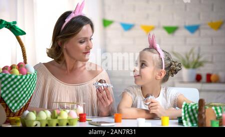 Schönen Mutter und Tochter in den lustigen Stirnbänder essen Ostern Schokolade Eier Stockfoto