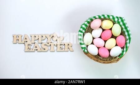 Frohe Ostern Holzschild und Korb mit bunten Ostereiern auf Tabelle Stockfoto
