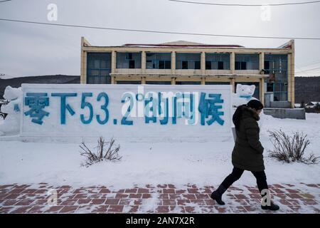 Harbin, Heilongjiang Provinz Chinas. 12 Jan, 2020. Eine Frau geht durch den Schnee Skulptur, die markiert den niedrigsten tempeture in der Geschichte hier in Bishui Stadt, Stadtteil Huzhong Dahinggan, im Nordosten der chinesischen Provinz Heilongjiang, Jan. 12, 2020. Huzhong Bezirk ist einer der kältesten Orte in China, die sich am nördlichen Fuß des Berges in Yilehuli Dahinggan. Die durchschnittliche jährliche Temperatur ist hier minus 4,3 Grad Celsius und die niedrigste Temperatur in der Stadt in der Geschichte war minus 53,2 Grad Celsius. Credit: Zhang Tao/Xinhua/Alamy leben Nachrichten Stockfoto