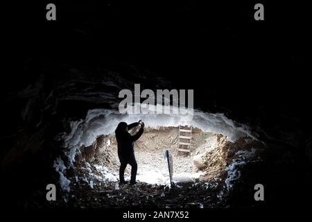 Harbin, Heilongjiang Provinz Chinas. 12 Jan, 2020. Ein Tourist nimmt Fotos von Eis in einer Höhle in Huzhong Bezirk, Dahinggan, im Nordosten der chinesischen Provinz Heilongjiang, Jan. 12, 2020. Huzhong Bezirk ist einer der kältesten Orte in China, die sich am nördlichen Fuß des Berges in Yilehuli Dahinggan. Die durchschnittliche jährliche Temperatur ist hier minus 4,3 Grad Celsius und die niedrigste Temperatur in der Stadt in der Geschichte war minus 53,2 Grad Celsius. Credit: Zhang Tao/Xinhua/Alamy leben Nachrichten Stockfoto