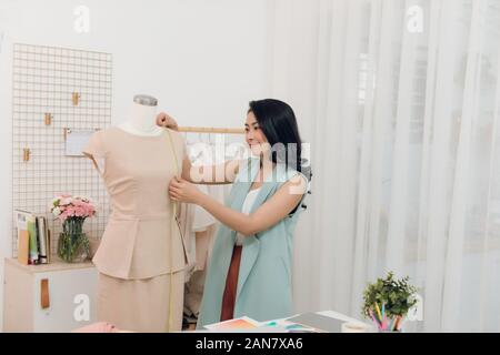 Junge asiatische Frau Modedesigner von Messungen an Mannequin in Ihrem Studio Stockfoto