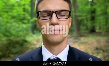 Geschäftsmann mit geschlossenen Augen in den Wald, zu träumen, in der Natur zu arbeiten, in der Nähe Stockfoto