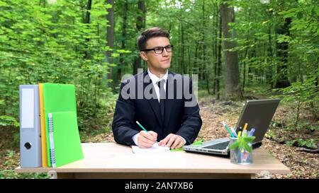Junge Unternehmer schreiben gute Ideen, im Büro Schreibtisch im grünen Wald arbeiten Stockfoto