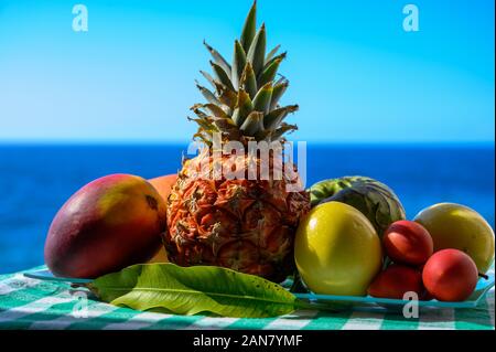 Tropische Früchte Sammlung, Custard Apple oder Grün reif cherymoia, Maracuja, Ananas, Mango, tamarillo Exotische Früchte auf blaues Meer Hintergrund in Stockfoto