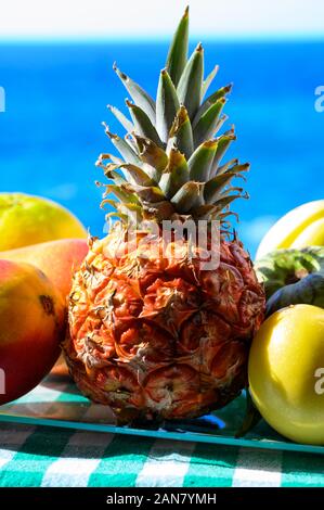 Tropische Früchte Sammlung, Custard Apple oder Grün reif cherymoia, Maracuja, Ananas, Mango, tamarillo Exotische Früchte auf blaues Meer Hintergrund in Stockfoto