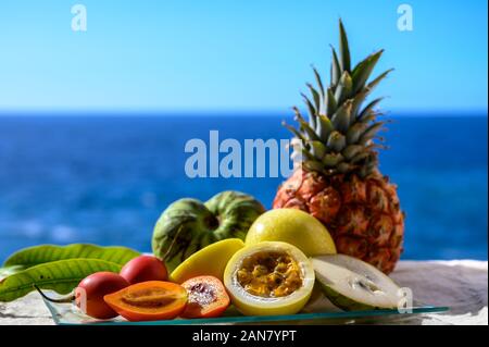 Tropische Früchte Sammlung, Custard Apple oder Grün reif cherymoia, Maracuja, Ananas, Mango, tamarillo Exotische Früchte auf blaues Meer Hintergrund in Stockfoto