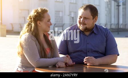 Junger Mann streicheln Freundinnen Hand, romantisches Date im Café draußen, Zweisamkeit Stockfoto