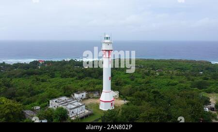 Leuchtturm auf einem Hügel in der Nähe des Meeres. Ozean Küste mit Regenwald und den Leuchtturm. Leuchtturm auf einer tropischen Insel, Ansicht von oben. Cape Bolinao Leuchtturm, Luzon, Philippinen. Sommer und Reisen Urlaub Konzept. Stockfoto