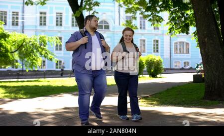 Fat Studenten wandern in Campus Park und reden, flirten auf Datum, Freundschaft Stockfoto