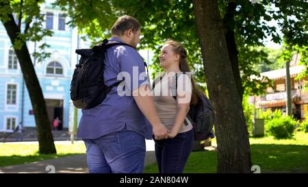 Junge übergewichtige Mann und Frau halten sich an den Händen und an einander mit der Liebe Stockfoto