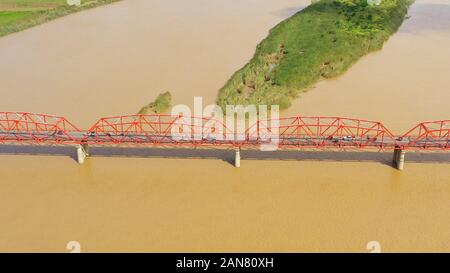 Autos fahren auf der Brücke. Breiten Fluss auf der Insel Luzon, Philippinen, Luftbild. Brücke über den Fluss. Landschaft, landwirtschaftliche Felder in der Nähe des Flusses. Stockfoto