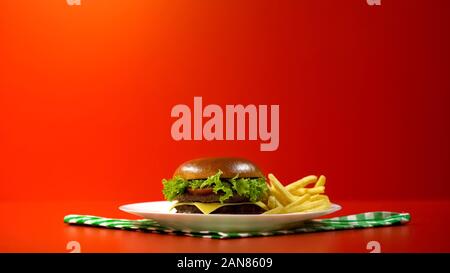 Lecker Hamburger serviert mit Pommes frites in Cafe, Platte auf kariert Serviette Stockfoto