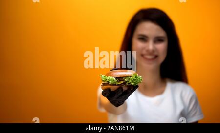 Mädchen in Handschuh Burger mit Kamera, lecker Essen, gute Qualität Service Stockfoto