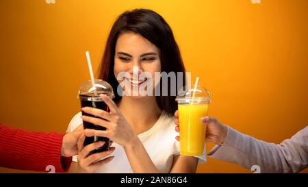 Fröhliches Mädchen Auswahl Soda statt Orangensaft, Neigung zu süße Getränke Stockfoto