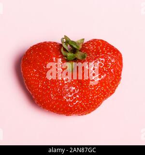 Rote Erdbeeren in der Form eines Herzens auf rosa Hintergrund. Valentinstag Konzept Stockfoto