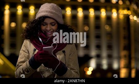 Fröhliche Frau der Ohrhörer Beobachten und Kommentieren von Fotos in sozialen Medien Stockfoto