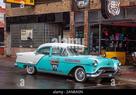 Williams, Arizona, USA. 23. Mai 2019. Blue Antique Car geparkt ist, ein verschneiter Tag, vor einem Souvenir shop in der Stadt, auf der berühmten Route 66. Alten Ziegel Stockfoto