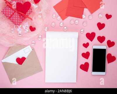 Geschenk in roter Geschenkbox mit Schleife, Notepad, Smart Phone, Umschlag, Karte, rote Herzen, rosa Hintergrund, Flach, kopieren Raum Stockfoto