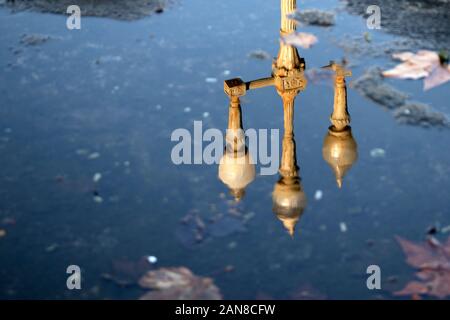 Reflexion einer Vintage Straßenlampe in einer Puddle mit Herbstlaub Stockfoto