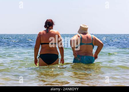 Kertsch, Russland - 12 August 2019: Zwei Frauen stehen im Meer an einem heißen Sommertag, Ansicht von der Rückseite Stockfoto