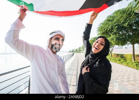 Glückliches Paar wandern in Dubai. Mann und Frau Holding VAE Flagge. Konzept über die Beziehung in den VAE Stockfoto