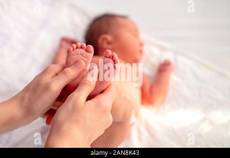 Vater oder Arzt kleine Babys Fuß massieren Stockfoto