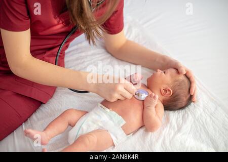 Pädiatrische Arzt Prüfungen neugeborenes Mädchen mit Stethoskop im Krankenhaus Stockfoto