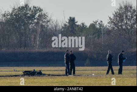 Strausberg, Deutschland. 16 Jan, 2020. Polizisten und forensische Techniker stehen neben die verkohlten Überreste eines kleinen Flugzeug auf dem Gelände des Flugplatz Strausberg. Zwei Menschen starben beim Absturz eines Kleinflugzeugs auf dem Flugplatz in Strausberg, Brandenburg. Als die Feuerwehr am Donnerstag weiter mitteilte, wurden keine weiteren Verletzten. Warum das Flugzeug stürzte zunächst unklar blieb. Foto: Patrick Pleul/dpa-Zentralbild/ZB/dpa/Alamy leben Nachrichten Stockfoto