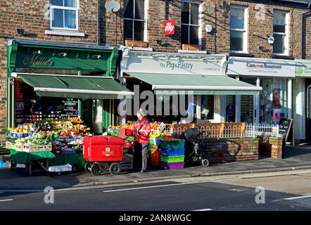 Postwoman Zustellung von Mails zu Geschäften auf Bishopthorpe Road, York, North Yorkshire, England, Großbritannien Stockfoto