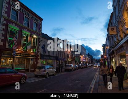 Killarney, Irland - 16. März 2018: Menschen, die in der Dämmerung durch die Straßen von Killarney gehen, Killarney ist ein beliebtes Touristenziel in Irland Stockfoto