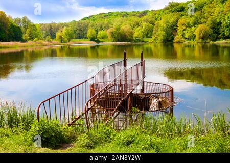 Hochwasserentlastung mit Metall Geländer auf den Wald See. Holosiivskyi Nationalpark in Kiew, Ukraine Stockfoto