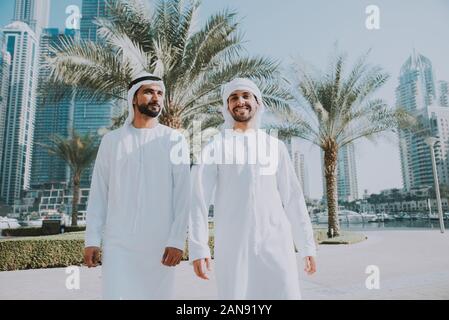 Zwei junge Unternehmer Ausgehen in Dubai. Freunde tragen Der kandura traditionelle männliche Outfit in Marina Stockfoto