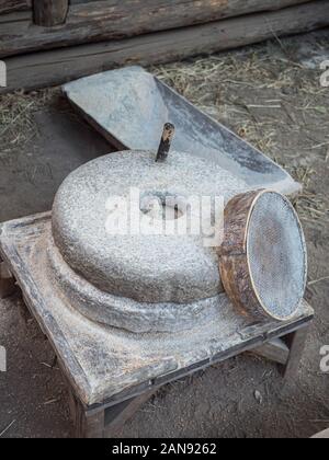 Rotary discoid Mill Stone für Hand- Schleifen einer Getreide zu Mehl. Mittelalterliche hand-driven Mühlstein mahlen Weizen. Die alten Quern Stein Hand Mühle mit Stockfoto