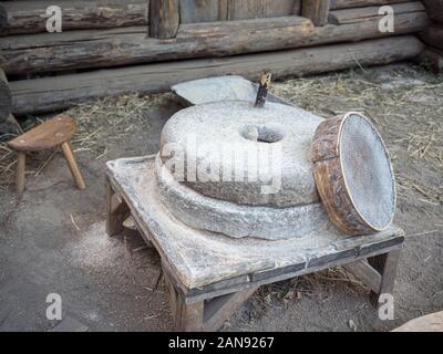 Rotary discoid Mill Stone für Hand- Schleifen einer Getreide zu Mehl. Mittelalterliche hand-driven Mühlstein mahlen Weizen. Die alten Quern Stein Hand Mühle mit Stockfoto