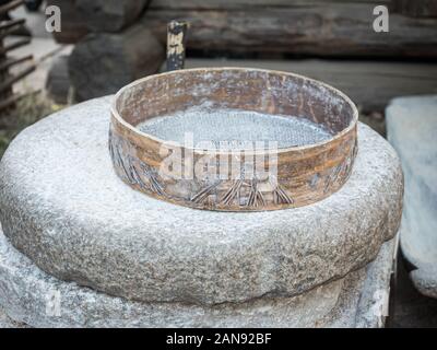 Rotary discoid Mill Stone für Hand- Schleifen einer Getreide zu Mehl. Mittelalterliche hand-driven Mühlstein mahlen Weizen. Die alten Quern Stein Hand Mühle mit Stockfoto