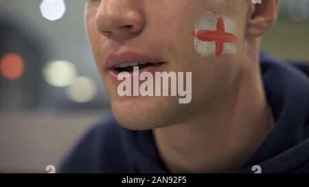 Fußball-Fan mit Englischer Flagge auf die Wange gemalt mit Begeisterung beobachten übereinstimmen Stockfoto