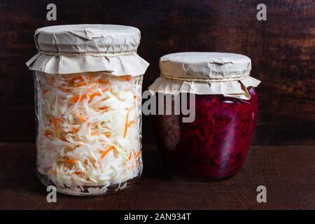 Hausgemachten Sauerkraut mit Karotten und Kohl Salat mit Rüben in einem Glas auf einem braunen Holz- Hintergrund. Fermentierter Lebensmittel. Stockfoto