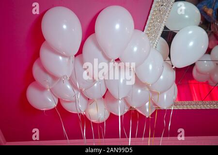 Hochzeit oder Kindergeburtstag Dekoration Interieur. Helium Luftballons rot schweben. weiße Ballons auf die weiße Decke im Zimmer Hin- und Herbewegung für die Stockfoto