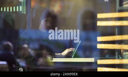 Attraktive Lady im hijab Arbeiten an Tablet, im Café sitzen, freie Projekt Stockfoto