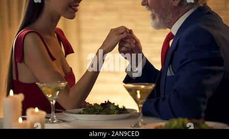 Älterer Herr die Hand von zarten jungen Frau, romantisches Date zusammen Stockfoto