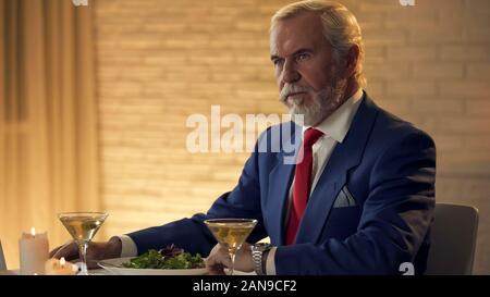 Stattliche reifer Mann im Anzug im Restaurant Sitzen, Warten auf Frau Stockfoto