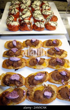 Madeleine Kekse mit Schokolade Butter Creme & gebrochen Blueberry Baisers und Weiße Schokolade Profiteroles auf Anzeige in ein Hotel Frühstücksbuffet. Stockfoto