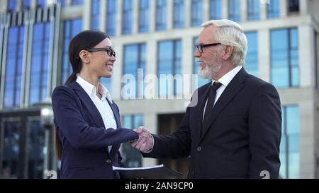 Ältere Unternehmer und junge weibliche Berater Handshaking, Vereinbarung der Genehmigung Stockfoto