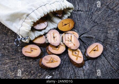Holz- Runen in einem Canvas Tasche auf ein alter Baumstumpf Stockfoto