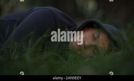 Obdachlose Männer schlafen auf Gras im Park, Armut und soziales Konzept Stockfoto