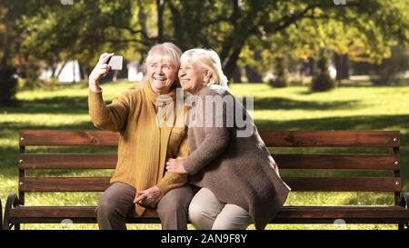 Zwei ältere Frauen, die selfie auf Handy, sitzt auf der Bank im Park Technology Stockfoto