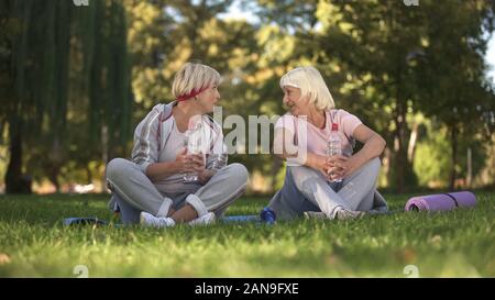 Mittleres Alter Frau und ihre Mutter sprechen, nachdem Übungen und Yoga im Park Stockfoto
