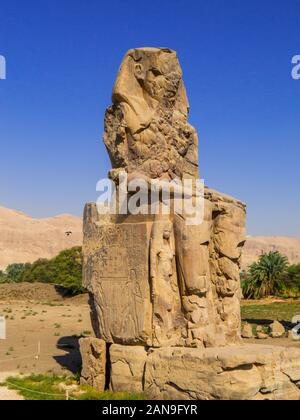 Angesichts der gigantischen Kolosse von Memnon (links Statue) im Totentempel von Amenophis III in Luxor, Ägypten Stockfoto