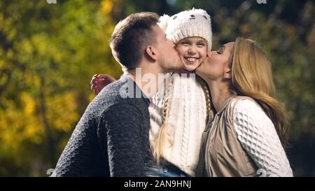 Glückliche Eltern kiss fröhliche Tochter im Herbst Park, wohlhabenden Familie, Wohlbefinden Stockfoto
