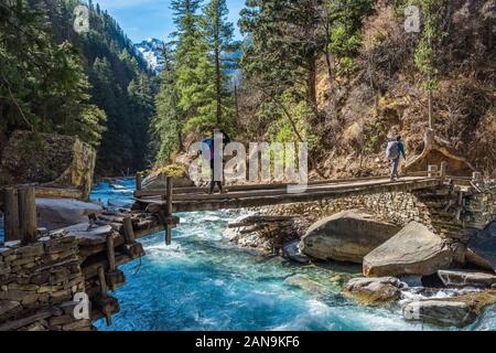 Trekker, die eine Holzbrücke auf dem unteren Dolpo-Trek im Nepal Himalaya überqueren Stockfoto